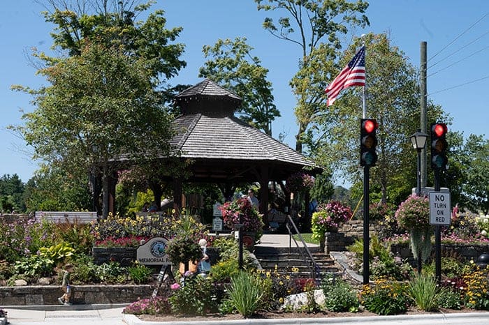 A gazebo with flowers and trees in the background.