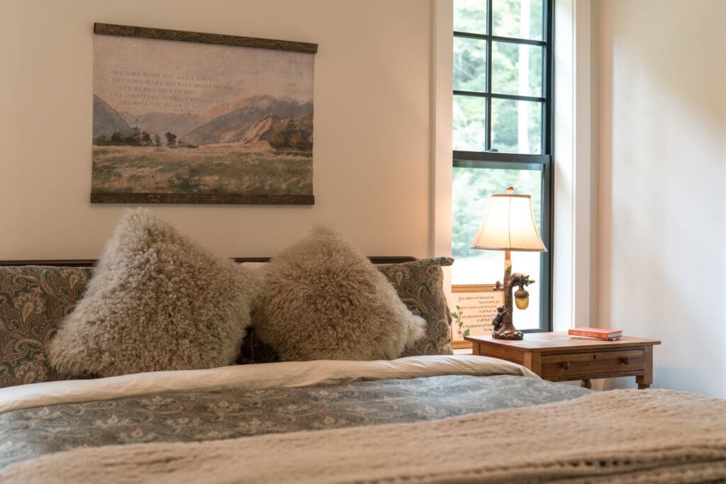 Cozy bedroom with fluffy pillows and lamp.