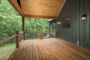 Wooden deck with forest view and railing.