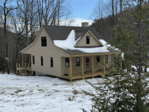 House surrounded by snow-covered landscape and trees.